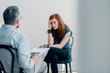 © Photographee.eu - Scared young woman talking to a therapist about abuse in a bright office