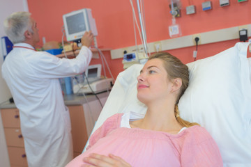 beautiful young pregnant woman sitting in a hospital bed