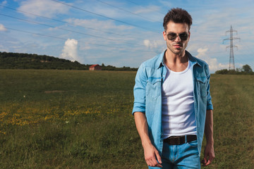 Wall Mural - portrait of casual man with sunglasses standing on a field