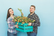 © satura_ - Happy florists fixing tulips in a big wooden box on blue background