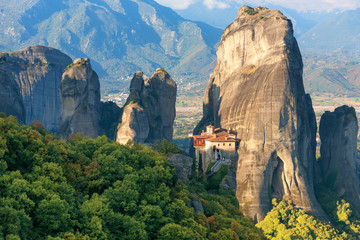 Beautiful scenic view, Orthodox Monastery of Rousanou (St. Barbara), immense monolithic pillar, green and yellow foliage at the background of stone wall in Meteora, Greece, Europe