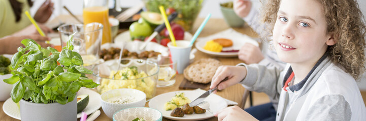 Close-up of a young boy eating a healthy lunch at a colorful table during a birthday party