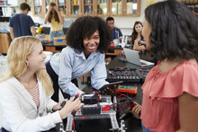 Teacher With Female Pupils Building Robotic Vehicle In Science Lesson