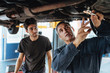 Two mechanics repairing a car.