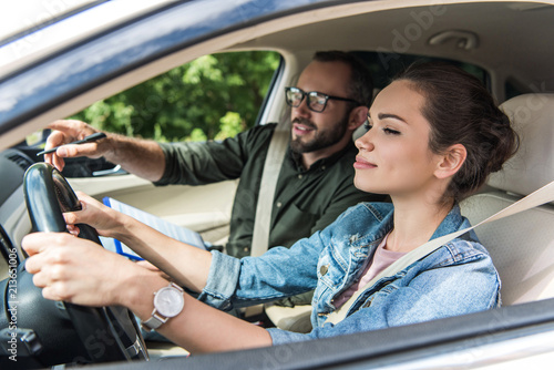 Fotografía cheerful student and teacher in car at driving test