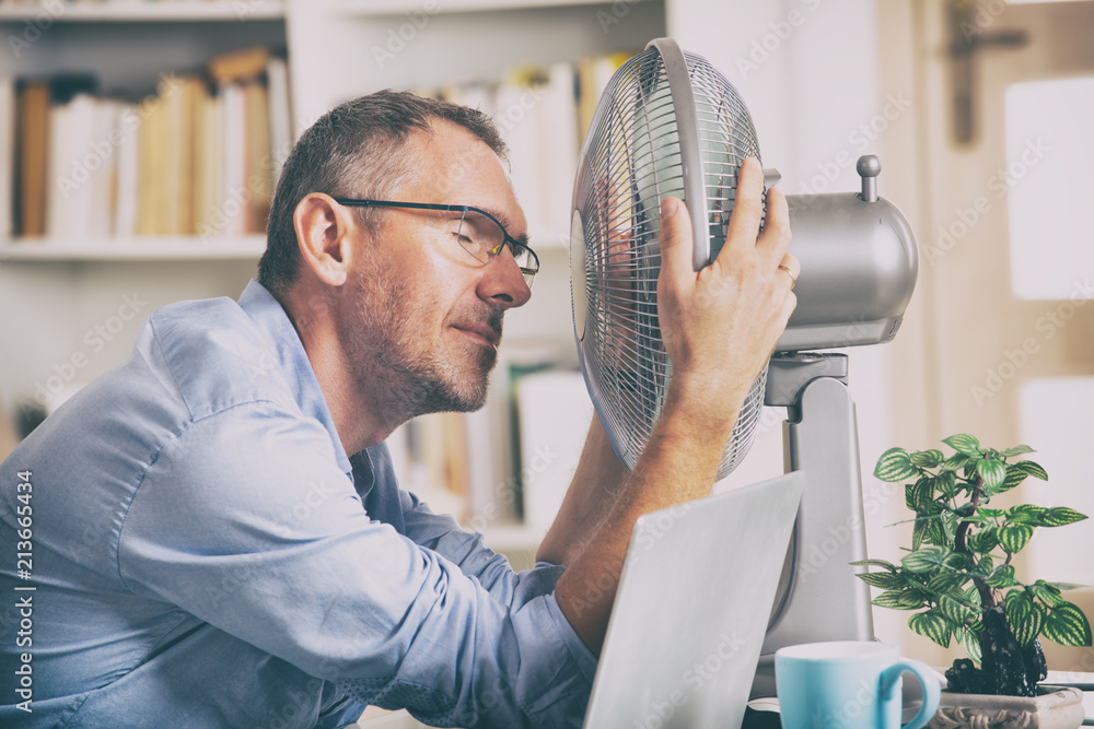 Man suffers from heat in the office or at home - obrazy, fototapety, plakaty 