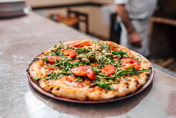 Delicious pizza on the plate. Chef in the background.