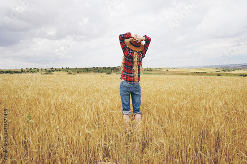 Fotografie, Obraz Vista posterior de una mujer joven en un campo de trigo