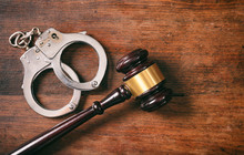 Handcuffs Isolated  And A Gavel With Copy Space On A Wooden Background.