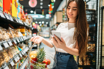 Wall Mural - Female customer uses mobile phone in supermarket