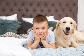 Wall Mural - Cute little child with his pet on bed at home