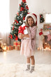 © New Africa - Cute little child in Santa hat with Christmas gift box at home