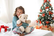 © New Africa - Cute little child with toy bear and Christmas gift box sitting on bed at home