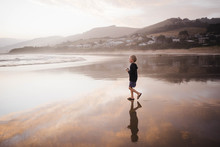 Boy Looking Walking At Beach Against Sky During Sunset