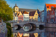 © Kavalenkava - Scenic city view of Bruges canal with beautiful medieval colored houses, bridge and reflections in the evening gold hour, Belgium