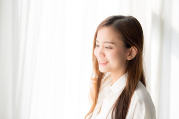 Wall Mural - Portrait of beautiful young asian woman standing the window and smile while wake up with sunrise at morning, lifestyle and relax concept.