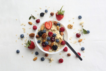 Oatmeal porridge in bowl topped with fresh blueberries, cranberries and homemade crunchy granola