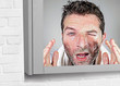 © TheVisualsYouNeed - young attractive and funny man washing face with soap with itchy eyes and messy face expression applying beauty facial skin care
