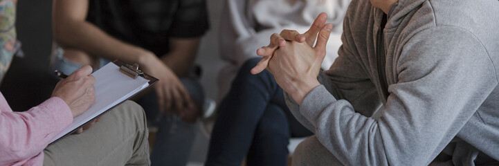 Panorama of therapist talking wiith agressive young man during meeting