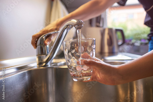Zdjęcie XXL Zakończenie up kobiety i dzieci ręki, nalewa szkło świeża woda od klepnięcia w kuchni