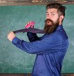 Hipster teacher formal wear necktie holds stapler. School stationery. Man scruffy use stapler dangerous way. Teacher bearded man with pink stapler chalkboard background. School accident prevention
