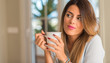 © Krakenimages.com - Young beautiful woman smiling and thinking holding a cup of coffee at home