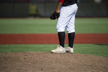 close up of baseball players legs with black stockings standing on first base