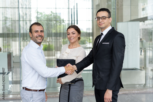 Fotografía Happy business people shaking hands and looking at camera