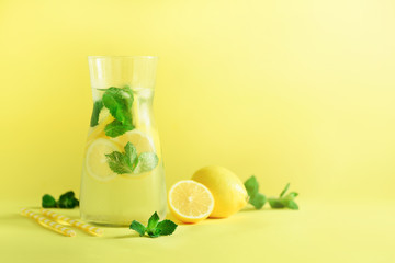 Wall Mural - Detox water with mint, lemon on yellow background. Banner with copy space, sunlight bokeh. Citrus lemonade. Summer fruit infused water.