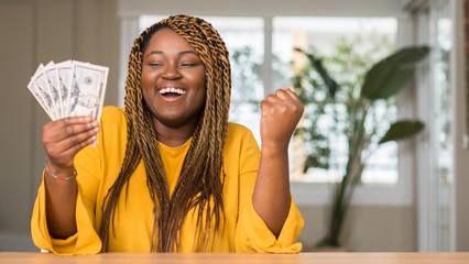 Poster - African american woman holding dollars screaming proud and celebrating victory and success very excited, cheering emotion