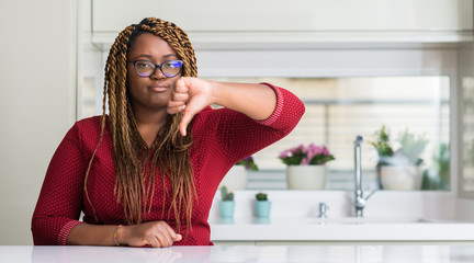 Sticker - African american woman sitting at home with angry face, negative sign showing dislike with thumbs down, rejection concept