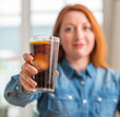 © Krakenimages.com - Redhead woman holding soda refreshment with a confident expression on smart face thinking serious