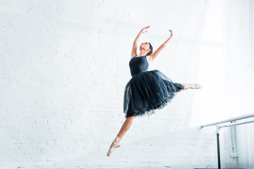 Wall Mural - low angle view of beautiful young ballerina dancing in ballet studio