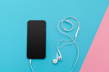 Creative flat lay photo of workspace desk with earphones and mobile phone