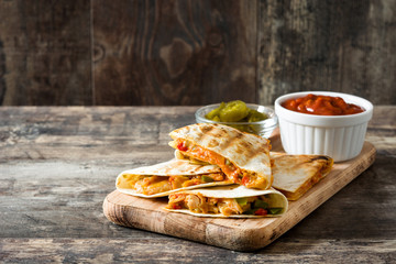 Wall Mural - Mexican quesadilla with chicken, cheese and peppers on wooden table. Copyspace