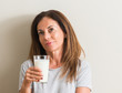 © Krakenimages.com - Middle age woman drinking a glass of fresh milk serious face thinking about question, very confused idea