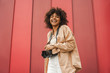 © LIGHTFIELD STUDIOS - low angle view of cheerful young african american woman holding camera and smiling at camera