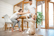 © rh2010 - Young couple playing with dog during a breakfast in the dining room of their beautiful wooden country house