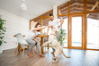 © rh2010 - Young couple playing with dog during a breakfast in the dining room of their beautiful wooden country house