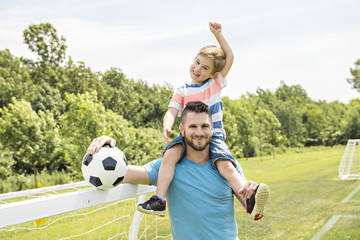 Wall Mural - Man with child playing football outside on field