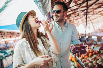 Young couple buying fruits and vegetables in a market on a sunny morning.