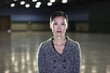 © Mint Images - An Asian businesswoman  standing in a dimly lit and dark exhibition area in a convention center.
