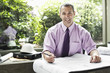 © Mint Images - A Caucasian businessman working on architectural plans in his office.