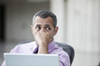 © Mint Images - A Caucasian businessman pondering a problem while working on a laptop computer.