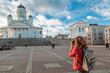 A beautiful young woman traveler with a camera on Senate Square in Helsinki, the capital of Finland, a popular destination for traveling to Northern Europe