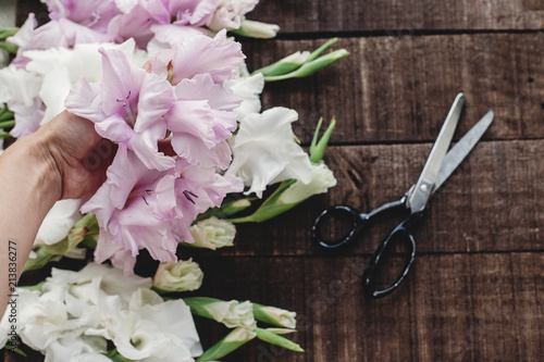 Fotografía hand holding beautiful pink and white gladioluses on rustic wooden background