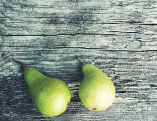 Two green ripe pears on an old wooden board, toned,  top view