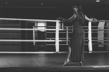 Wall Mural - Woman with boxing gloves on hands and dress, boxing in ring. Active girl fight. lady fight. monochrome