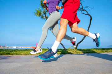 Running couple jogging on beach. Runners training together. Man and woman joggers exercising outdoors.