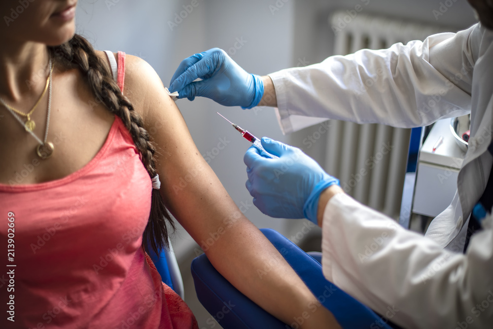 medico disinfetta la pelle di una paziente prima di fare una vaccinazione - obrazy, fototapety, plakaty 